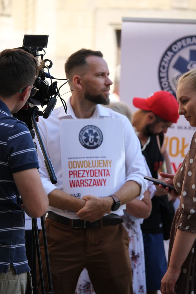Maciej Wilk z plakatem kampanii rozmawia z dziennikarką